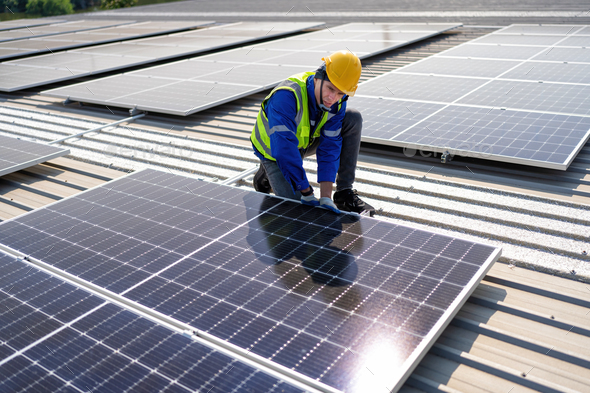 Engineer on rooftop kneeling next to solar panels photo voltaic with ...