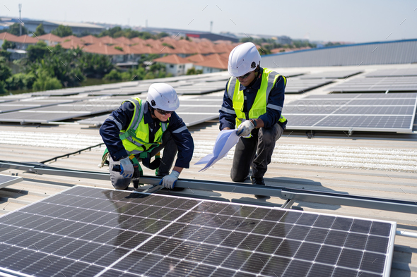 Engineer on rooftop kneeling next to solar panels photo voltaic check ...