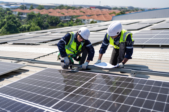 Engineer on rooftop kneeling next to solar panels photo voltaic check ...