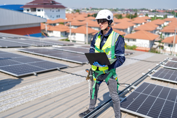 Engineer on rooftop standing next to solar panels photo voltaic check ...