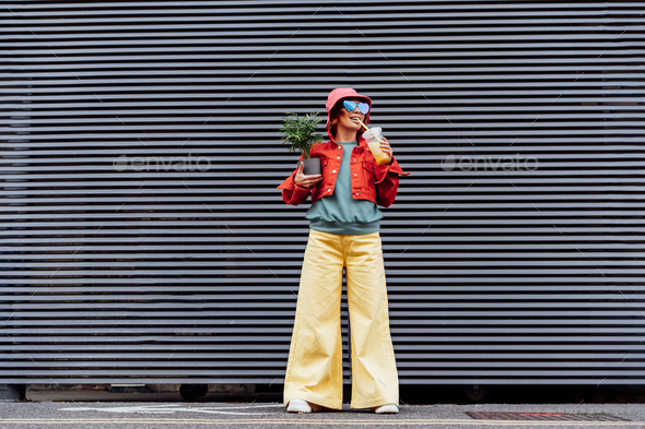 Hipster fashion woman in bright clothes, heart shaped glasses, bucket hat  drinking fruity bubble tea Stock Photo by Okrasyuk