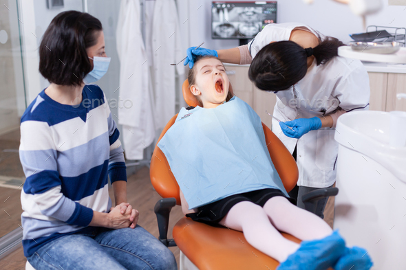 Little kid with mouth open and dentist looking for caries