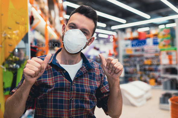 builder in hardware store buys mask for painting work, points at it with two fingers