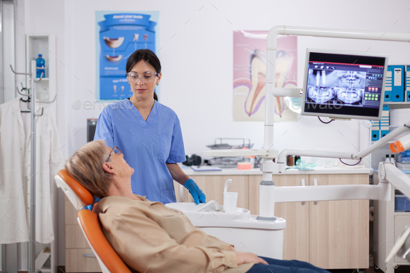 Assistant in dental clinic questioning elderly patient