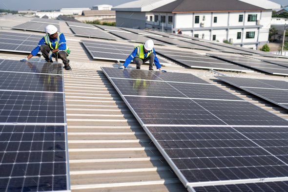 Engineer on rooftop sitting next to solar panels photo voltaic check ...