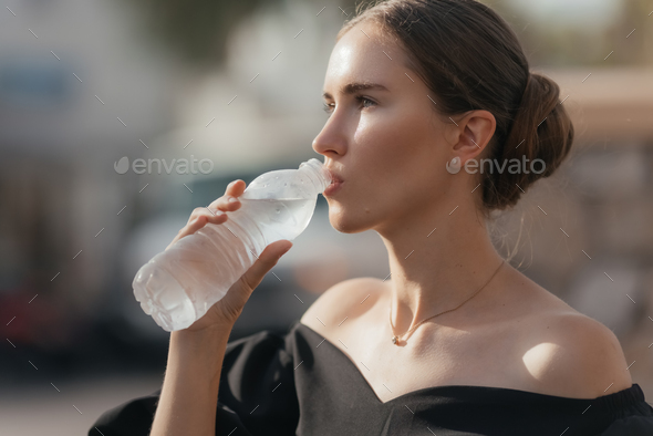 Beautiful woman resting after gym workout holding a plastic water bottle, Stock image