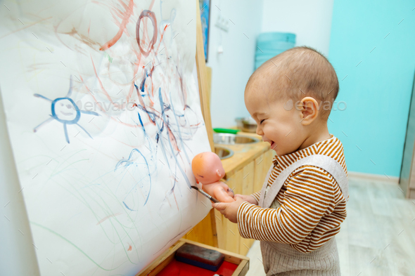 Toddler painting on a paper canvas Stock Photo by collab_media