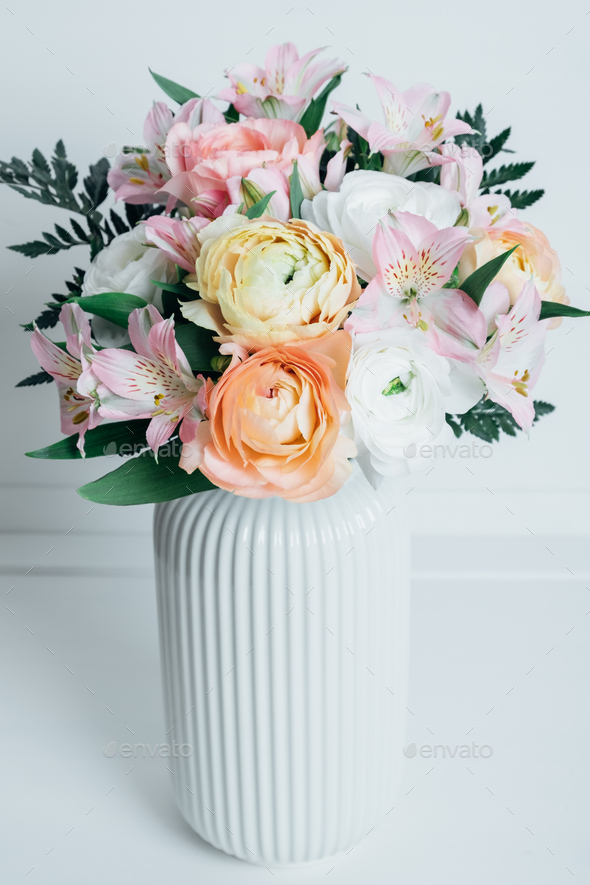 Beautiful colorful flowers in bloom in white vase.