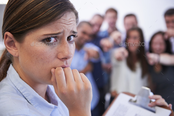 What do I do now. Closeup of an anxious young woman facing the accusatory fingers of her coworkers.