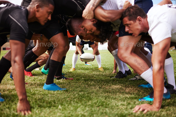 The battle begins. Shot of a group of young rugby players in a scrum on the field.