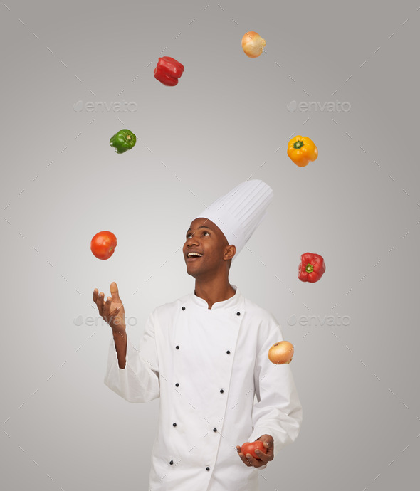 Tricks of the trade. A young African-American chef juggling with vegetables.