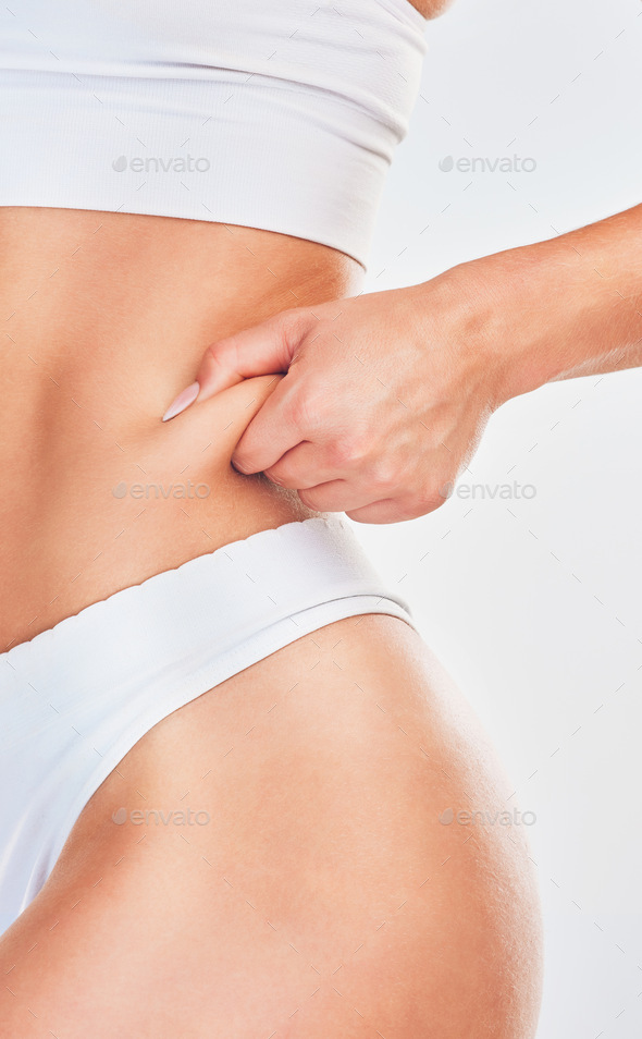 Hand, pinch and woman in underwear her belly fat for weight loss on a white  studio background. Over Stock Photo by YuriArcursPeopleimages