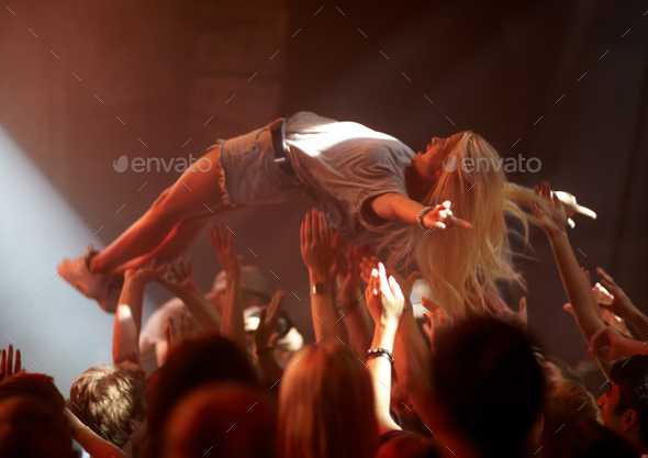 Surfing the crowd. A young woman crowd surfing at a concert.