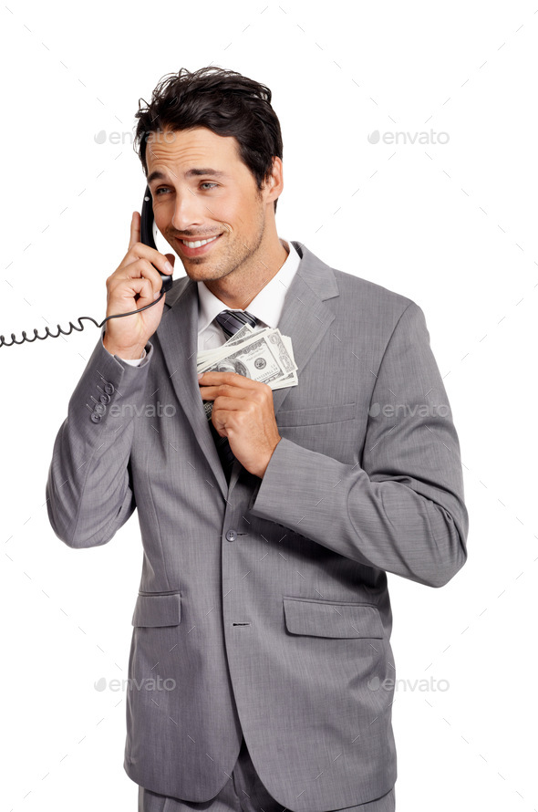 An unethical businessman shoving a wad of cash into his jacket pocket while on a telephone