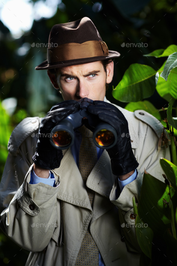 Checking up on you...Private investigator using binoculars to spy on someone from the bushes.