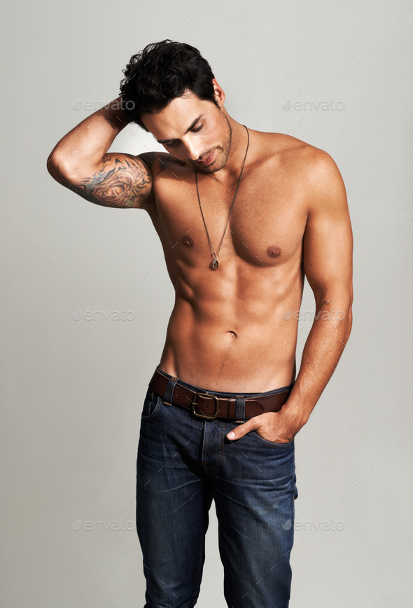 Barechested and hunky. A muscular young man standing shirtless with