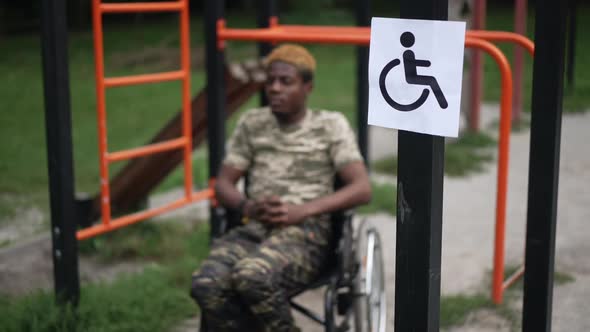 Disability Accessibility Sign on Sports Equipment in Park with African American Young Man in alt