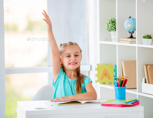 Beatiful little girl raised hand in classroom Stock Photo by tan4ikk