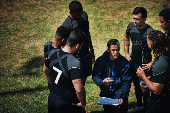 Cropped shot of a handsome young rugby coach addressing his team on the field during the day