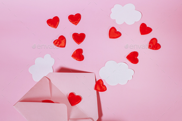 An open postal envelope with red hearts and clouds flying out of it. Hearts flying out of an open