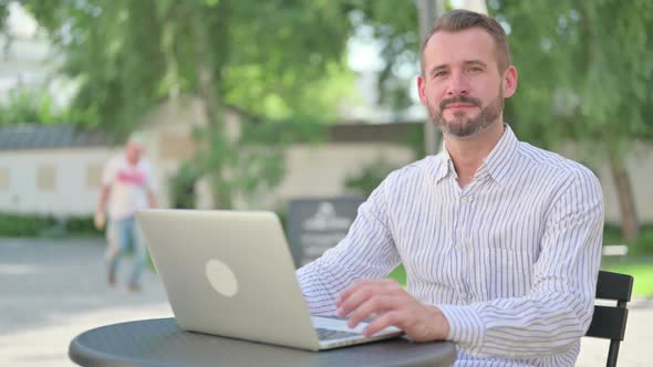 Middle Aged Man Shaking Head As Yes Sign in Outdoor Cafe alt