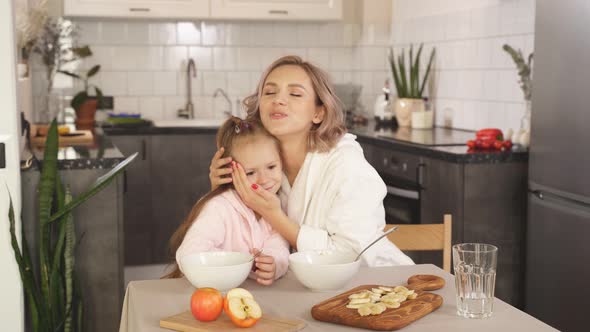Mother Hugs Her Little Daughter Sitting Table Kitchen She Praises Her Child Eating Porridge Mother alt