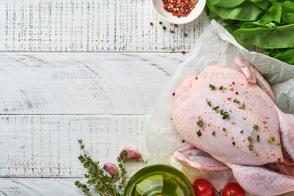 Whole raw chicken with ingredients for making rose pepper, lemon, thyme, garlic, cherry tomato, sorr