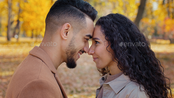 Loving married couple standing foreheads touched and rubbing noses enamored smiling happily outdoors