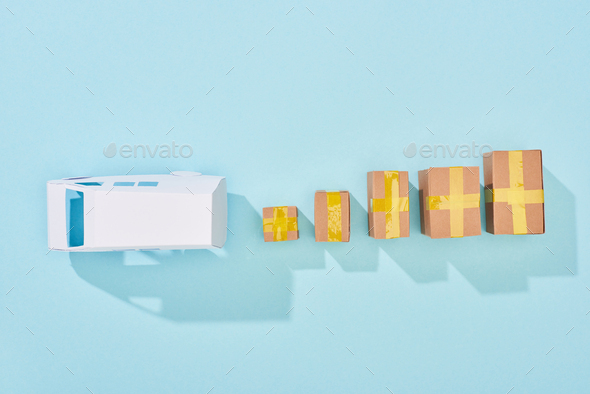 top view of white van model near closed cardboard boxes on blue background