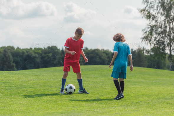 cute curly boy playing football with friend on grass Stock Photo by ...