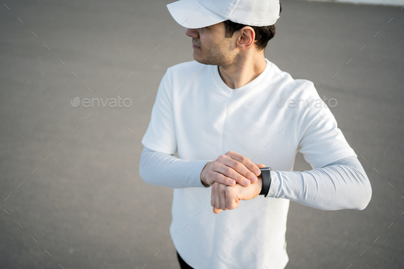 A male sports athlete uses a smartwatch on his hand to count calories and pulse while training