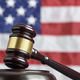 Close up of wooden judge gavel. American flag in background - PhotoDune Item for Sale
