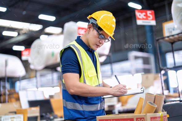 Worker working in large depot storage warehouse hold check list for packing box at cashier counter