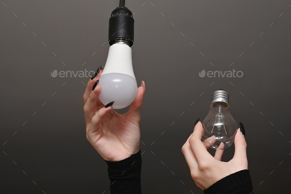 New LED lamp and incandescent lamp in women\'s hands. the concept of energy saving.