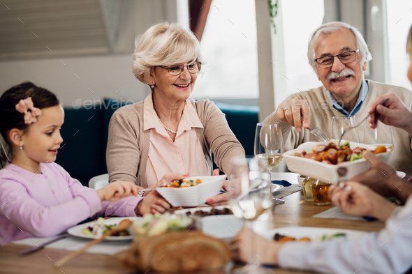 Happy Grandparents Having Lunch With Their Family At Dining Table 