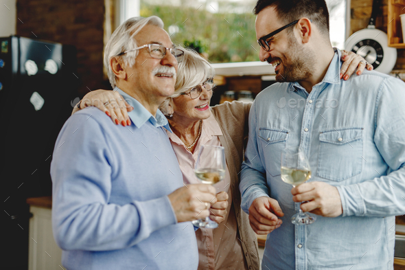 Happy Senior Parents With Their Adult Son In The Kitchen. Stock Photo 