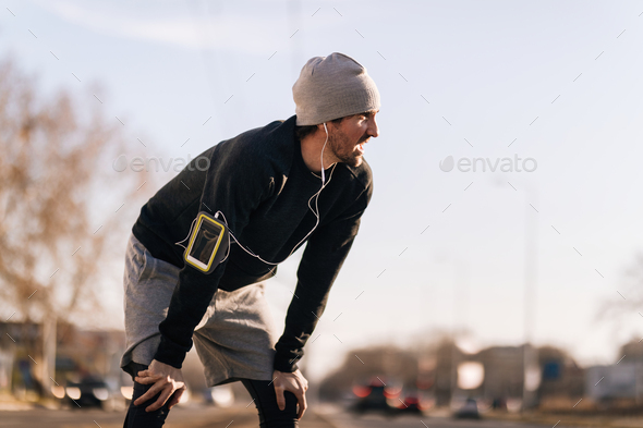 Young athletic man taking a break while running in the city.