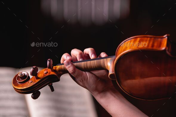 Ladies studies classical music on violin with fingers in front of the score.