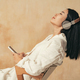 Side view of woman enjoying music in wireless headphones leaning her back on chair, holding phone - PhotoDune Item for Sale