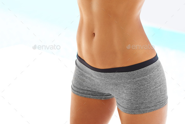 Cropped shot of a young slender woman with toned stomach with abs