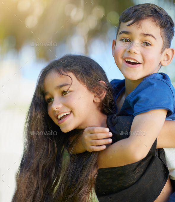 Young girl carrying sister giving piggyback ride Stock Photo