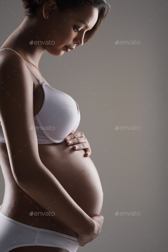 Studio shot of a beautiful young pregnant woman posing in underwear against  a gray background Stock Photo by YuriArcursPeopleimages