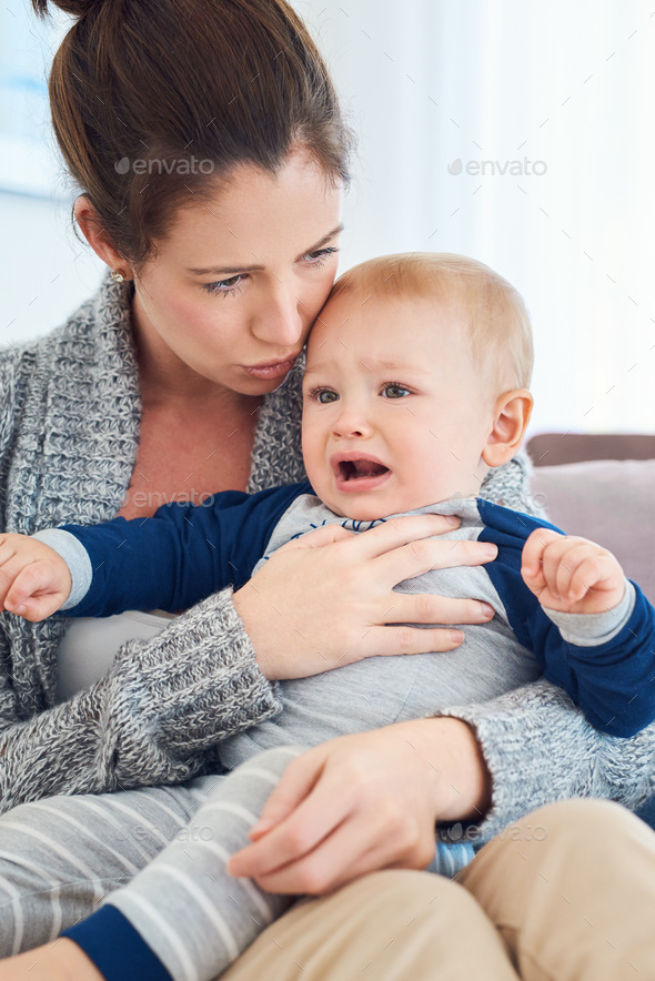 Cropped shot of a mother trying to console her crying baby boy at home ...