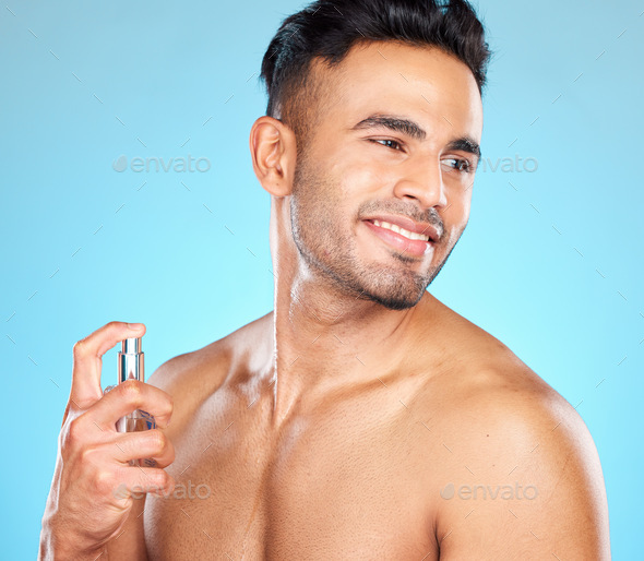 Man, happy and perfume for fragrance, aroma and manly scent on blue studio background. Young male,