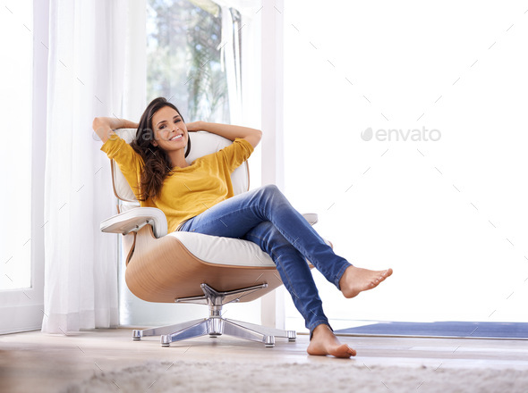 Taking it easy. A woman relaxing on a chair with her hands behind her head.