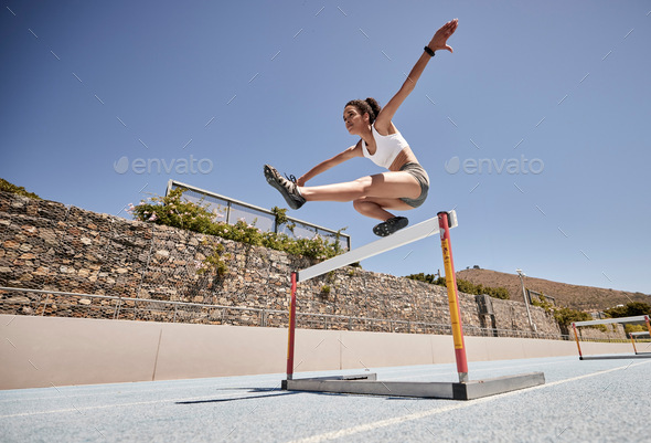 Runner, fitness and girl stadium jump for athlete hurdle training, workout or competition race. Cha