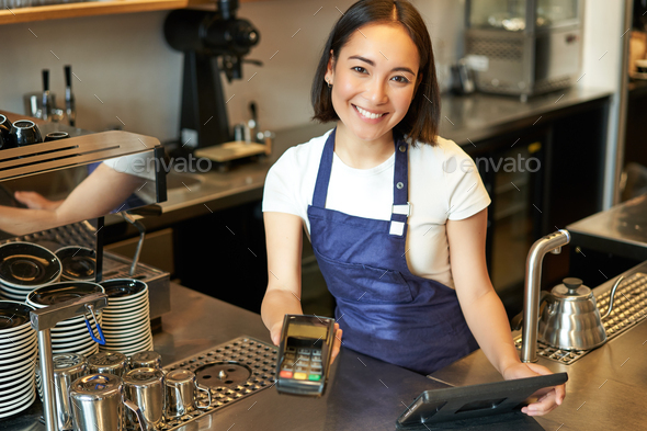 Happy smiling asian barista, girl behind counter, working with POS terminal  and brewing filter kit Stock Photo by benzoix