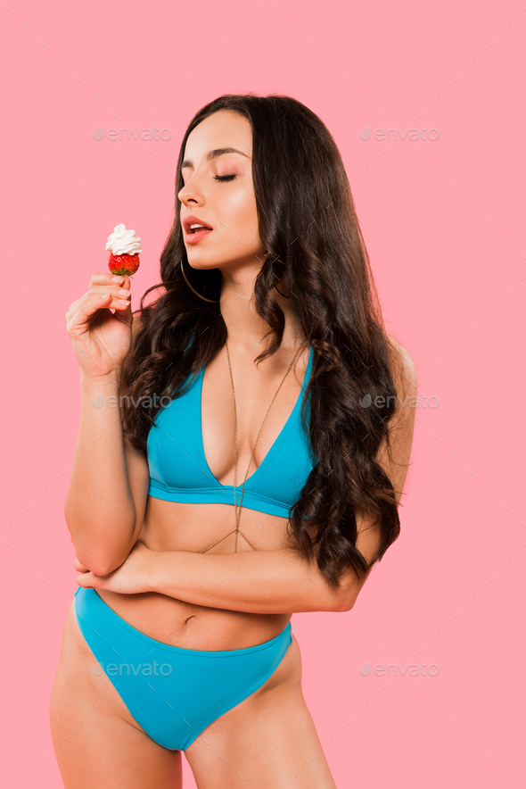 sexy girl holding strawberry with whipped cream isolated on pink