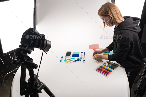 photographer making flat lay with office supplies for commercial photo  shooting on white Stock Photo by LightFieldStudios