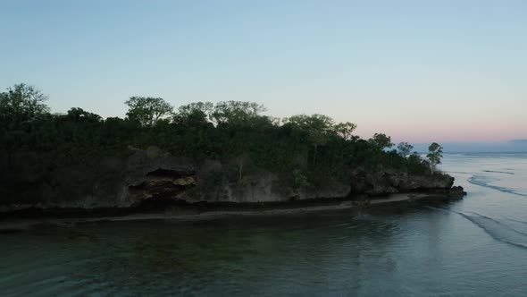 Title reveal shot over rocky peninsula on coast of Fiji during dawn, aerial alt